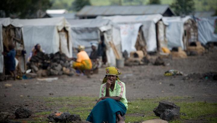 Een vrouw zit op een rots voor het Kibati vluchtelingenkamp vlakbij Goma, de hoofdstad van de Provincie Noord-Kivu. Bron: UNICEF