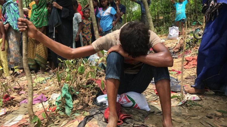 A Rohingya man crouches beside a bag of food aid donated by a Bangladeshi humanitarian organisation at an informal settlement close to Kutupalong refugee camp. ; As hundreds of thousands of Rohingya sought safety in Bangladesh between late-August and mid-September 2017, UNHCR began work on an extension site next to the long-established Kutupalong refugee camp in Cox’s Bazar. Whole families, young mothers and unaccompanied minors were among those fleeing for their lives since fighting reignited in Myanmar. They came by boat or walked barefoot for day, leaving most of their possessions behind. Large groups crossed into south-eastern Bangladesh hungry, in poor physical condition and in need of life-saving support. By mid-September, the Bangladeshi Government allocated some 2,000 acres of land, on which family tents and temporary communal shelters were erected to shelter new arrivals. UNHCR site planners estimate that these will be sufficient to house 150,000 of the estimated 415,000 people who have arrived in Bangladesh.